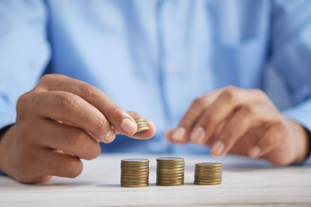 Earning More But Not Becoming Wealthy? Here’s What’s Missing Close-up of hands stacking gold coins, symbolizing financial growth and savings.