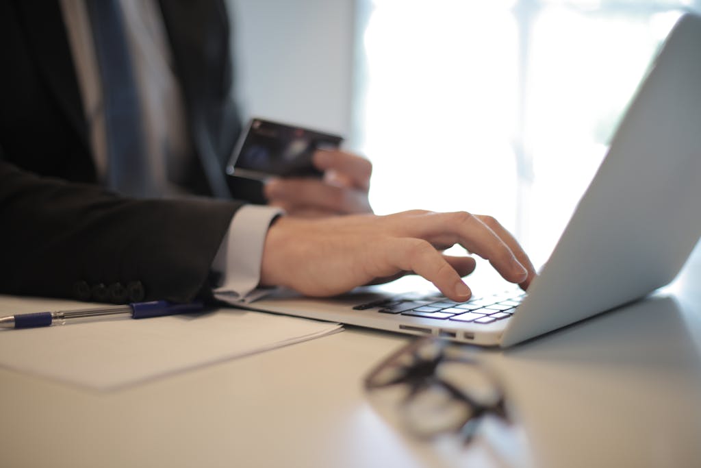 Why You Can’t Stop Impulse Buying (And What’s Really Behind It) Man in suit using laptop and credit card for online transaction at work.