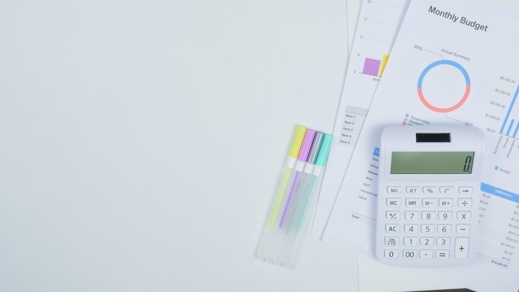 How to Build a Resilient Budget With Unpredictable Income Minimalist office desk with a calculator, budget planning documents, and colorful pens.